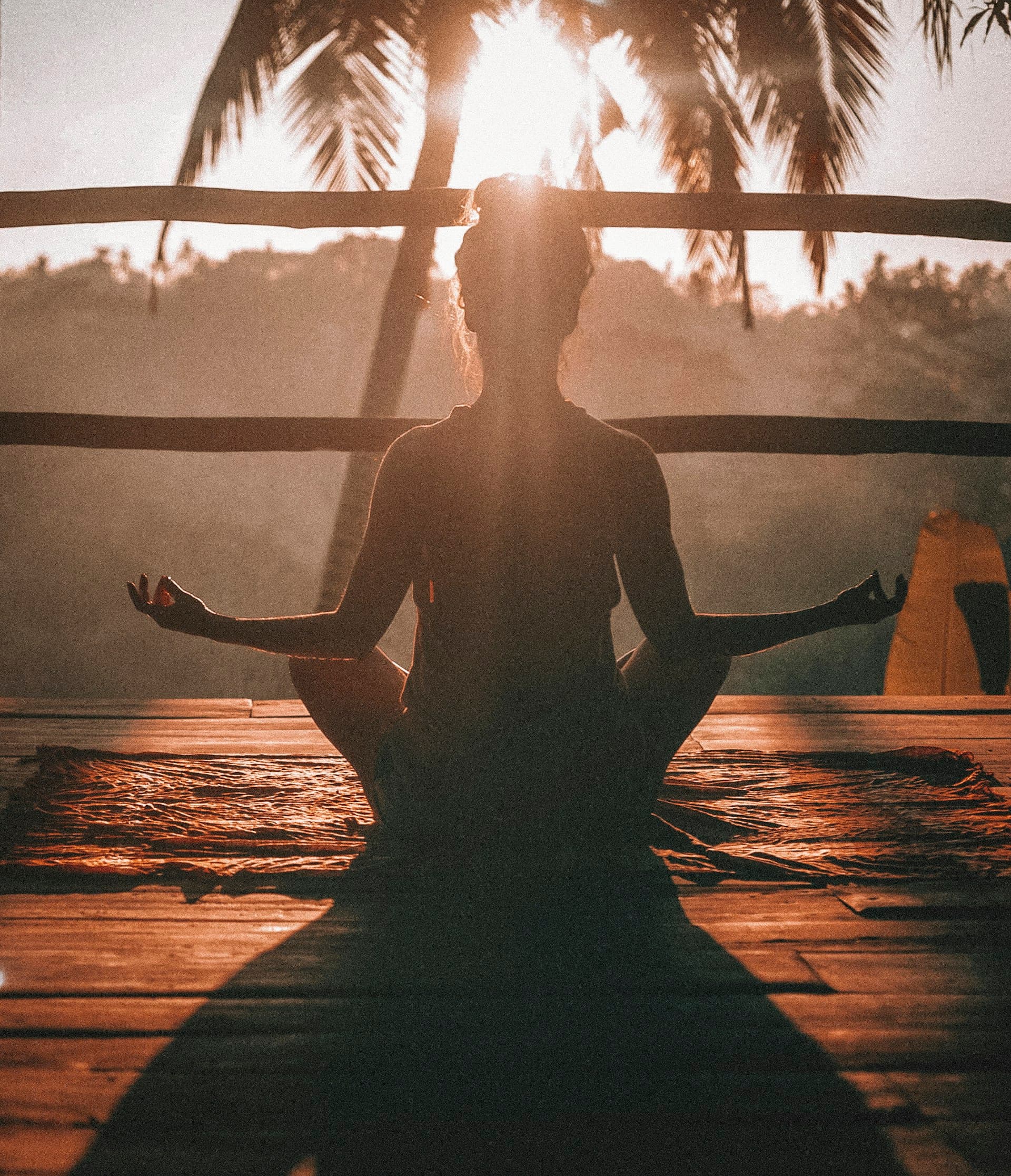 Donna in meditazione seduta al tramonto, controluce dorato